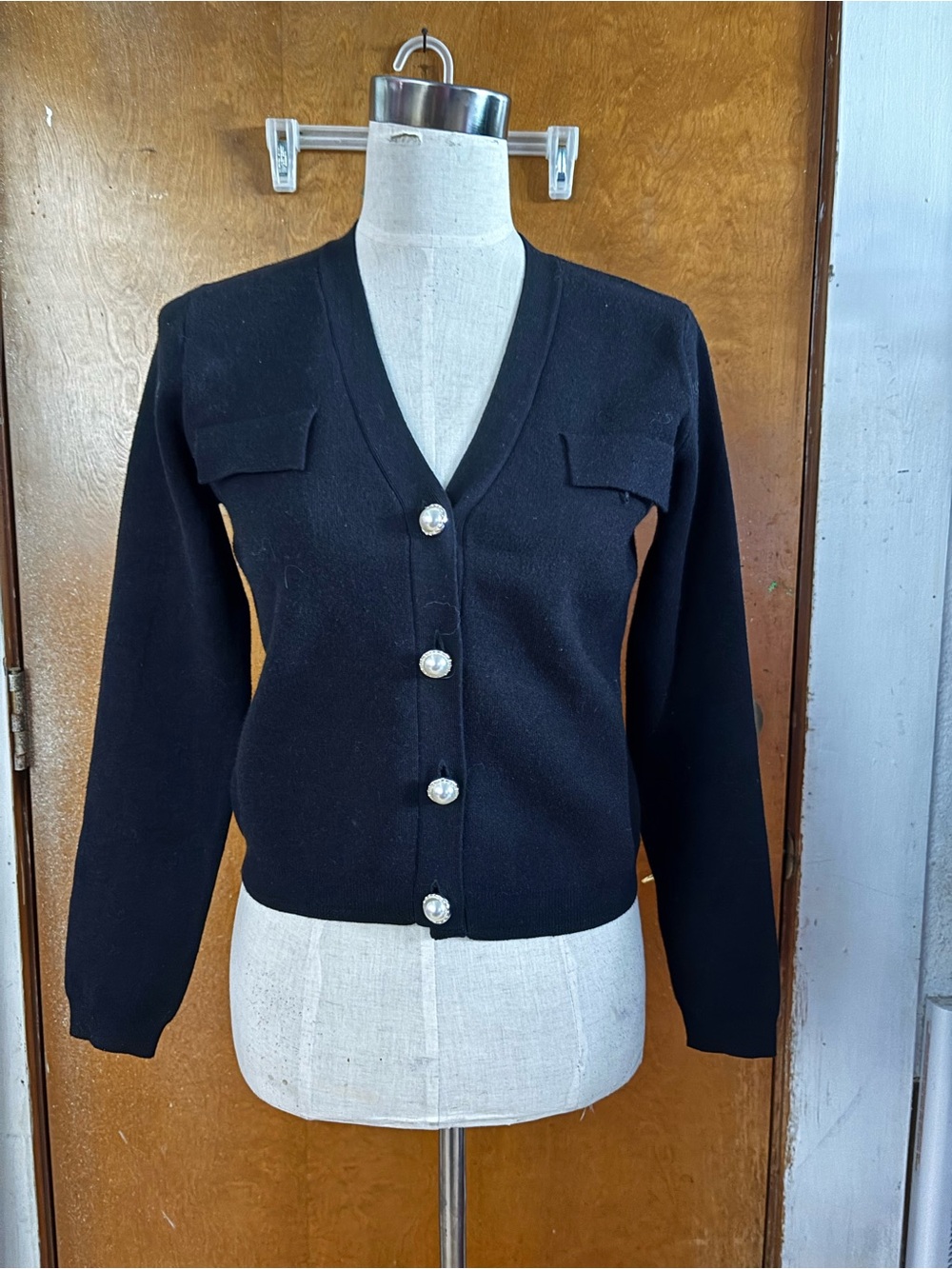 Black cropped cardigan with pearl buttons.